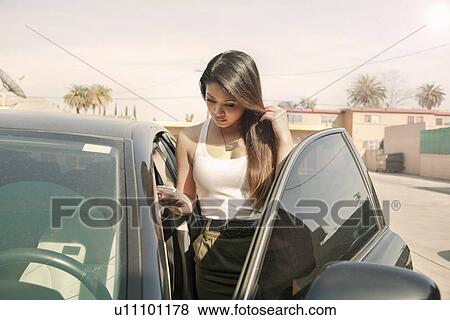 Young woman with smartphone, getting into car View Large Photo Image Stock Photo - Young woman with smartphone, getting into car. Fotosearch