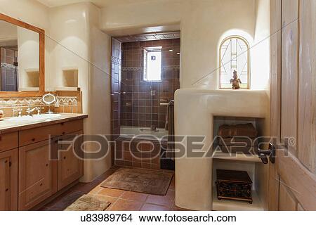 Picture - Brown cabinets and mirror with tiled bath in the background at bathroom; Santa Fe; New Mexico; USA. Fotosearch