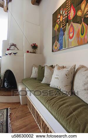 Stock Image - Built in couch with fireplace and painting at home; Santa Fe; New Mexico; USA. Fotosearch