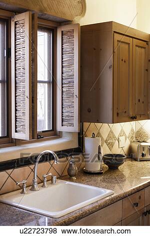 Stock Photo - Close-up of a faucet with washbasin and window in the kitchen; Santa Fe; New Mexico; USA. Fotosearch