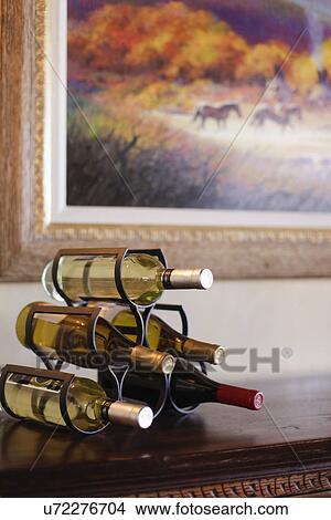 Picture - Close-up of alcohol bottles in rack on table against cropped painting; Santa Fe; New Mexico; USA. Fotosearch