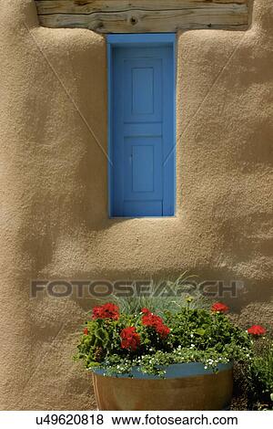 Stock Photo - Close-up of closed blue door with adobe wall and potted plant; Taos; New Mexico; USA. Fotosearch
