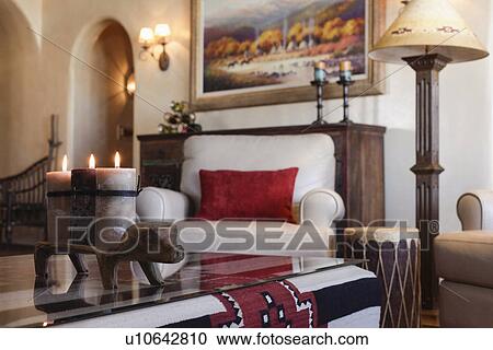 Stock Image - Close-up of lit candles on coffee table with upholstered armchair in living room; Santa Fe; New Mexico; USA. Fotosearch