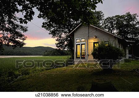 Stock Photograph - Exterior of a cabin with clapboard siding by lake at dusk; Burlington; Vermont; USA. Fotosearch