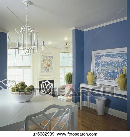 Hanging light over cropped dining table with painting against blue wall View Large Photo Image Stock Photo - Hanging light over cropped dining table with painting against blue wall. Fotosearch