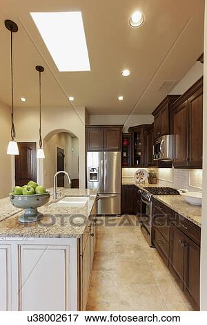 Stock Photo - Kitchen with brown cabinets and island at home; Santa Fe; New Mexico; USA. Fotosearch