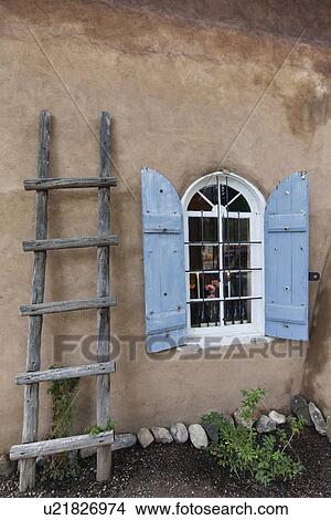 Picture - Ladder besides window with open shutters; Taos; New Mexico; USA. Fotosearch