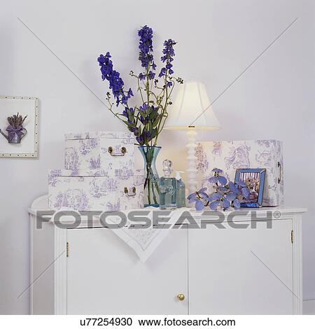 Stock Image - Lavender toile boxes; blue glass bottles and vase on white cabinet. Fotosearch