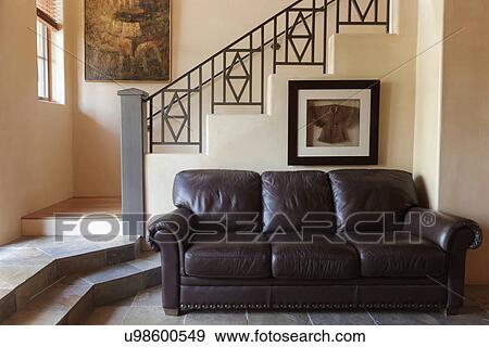 Stock Photo - Leather brown couch with stairs in background; Santa Fe; New Mexico; USA. Fotosearch
