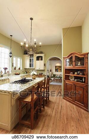Lit chandelier hanging over high stools at kitchen island at home; Santa Fe; New Mexico; USA View Large Photo Image Stock Photo - Lit chandelier hanging over high stools at kitchen island at home; Santa Fe; New Mexico; USA. Fotosearch