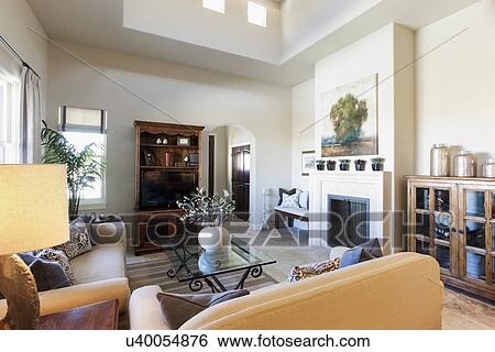 Stock Photograph - Living room with seating furniture; fireplace and shelf at home; Santa Fe; New Mexico; USA. Fotosearch