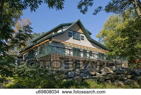 Low angle view of a house surrounded by trees against clear blue sky View Large Photo Image Picture - Low angle view of a house surrounded by trees against clear blue sky. Fotosearch