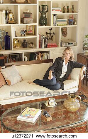 Stock Image - Portrait of a smiling woman relaxing in living room at home; Santa Fe; New Mexico; USA. Fotosearch