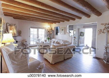 Stock Image - Seating furniture with exposed ceiling beams in spacious living room at home; Santa Fe; New Mexico; USA. Fotosearch