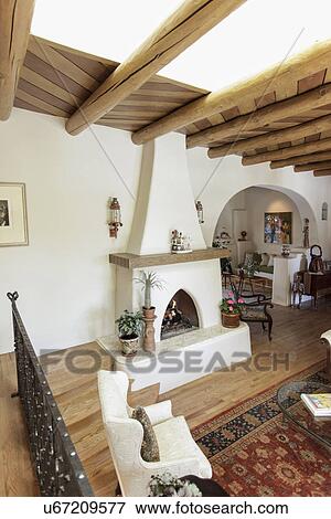 Stock Photo - Spacious living room with exposed ceiling beams and fireplace at home; Santa Fe; New Mexico; USA. Fotosearch