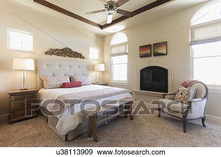 Stock Photo - Table lamps by tidy bed with fireplace in the bedroom at home; Santa Fe; New Mexico; USA. Fotosearch