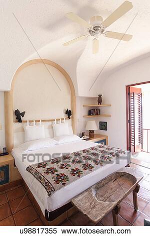Stock Photography - Tidy bed with ceiling fan in beach resort; Zihuateno; Mexico. Fotosearch