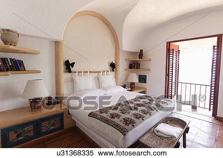 Stock Photography - Tidy bed with view of balcony in beach resort; Zihuateno; Mexico. Fotosearch