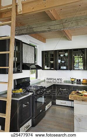 Picture - View of a kitchen having black cabinets at home; Burlington; Vermont; USA. Fotosearch
