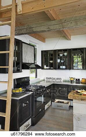 Picture - View of a kitchen having black cabinets at home; Burlington; Vermont; USA. Fotosearch