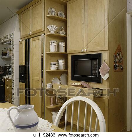 Stock Image - View of microwave with wooden cabinets and refrigerator. Fotosearch