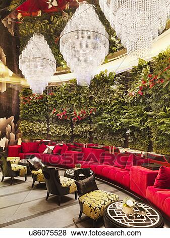 Stock Photo - Walled red sofa with crystal chandeliers and plants in restaurant. Fotosearch