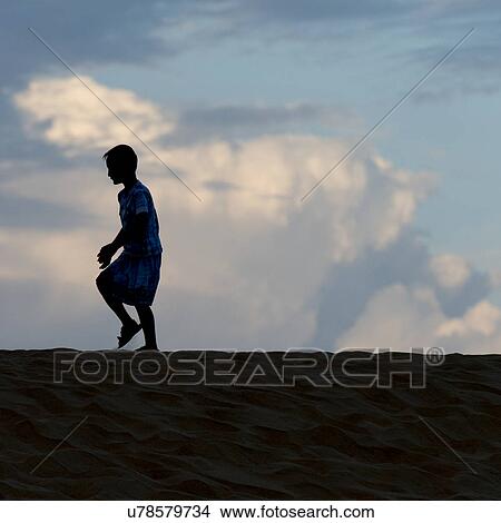 Picture - Boy walking on sand dune at Mingsha Shan, Dunhuang, Jiuquan, Gansu Province, China. Fotosearch