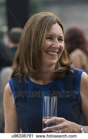 Stock Image - Caucasian woman holding a glass of water and smiling, Beijing, China. Fotosearch