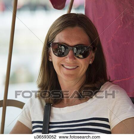 Stock Image - Close-up of a caucasian woman wearing sun glasses and smiling, Hutong, Beijing, China. Fotosearch