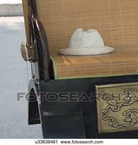 Stock Image - Close-up of a hat on the seat of a rickshaw, Hutong, Xicheng District, Beijing, China. Fotosearch
