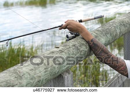 Stock Photo - Close-up of a person's arm holding a fishing rod, Riding Mountain National Park, Manitoba, Canada. Fotosearch