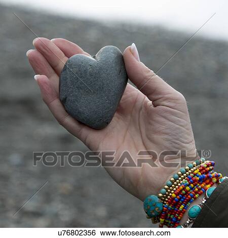Stock Photograph - Close-up of a woman's hand holding a heart shaped stone, Deception Pass State Park, Oak Harbor, Washington State, USA. Fotosearch