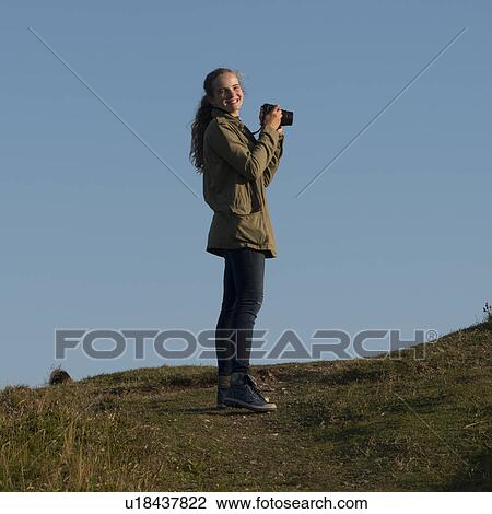 Stock Image - Girl taking pictures with camera, Skerwink Trail, Port Rexton, Bonavista Peninsula, Newfoundland And Labrador, Canada. Fotosearch