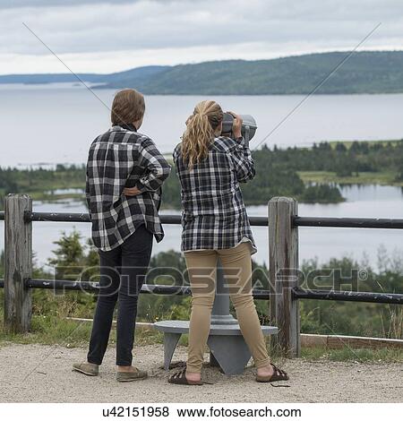 Stock Photo - Girls looking at bay view through a coin-operated binoculars, Joey's Lookout, Gambo, Newfoundland And Labrador, Canada. Fotosearch