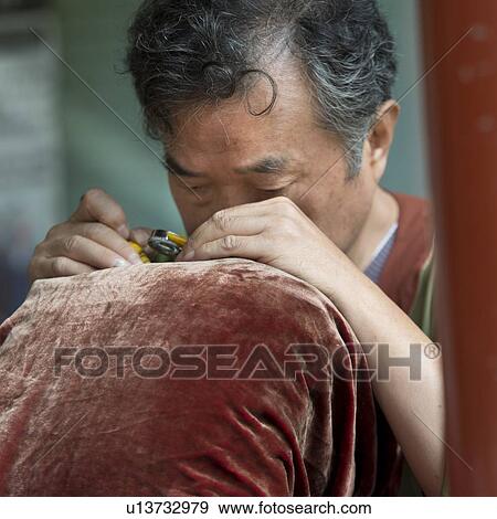 Stock Photo - Man embroidering, Suzhou Street, Summer Palace, Beijing, China. Fotosearch