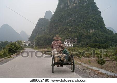 Man riding a cycle cart on road in town, Yangshuo, Guangxi Province, China View Large Photo Image Stock Image - Man riding a cycle cart on road in town, Yangshuo, Guangxi Province, China. Fotosearch