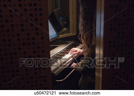 Stock Image - Teenage girl playing piano at EMP Museum, Seattle, Washington State, USA. Fotosearch