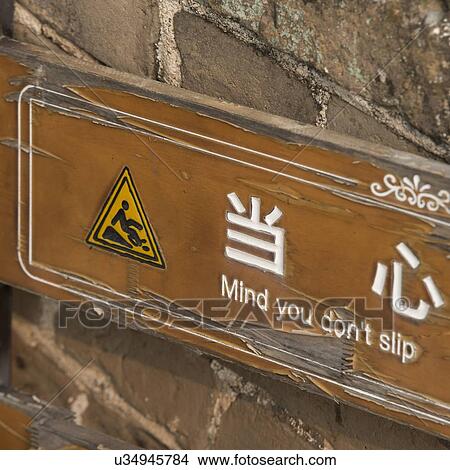 Picture - Warning sign with phrase 'Mind You Don't Slip' on Jinshanling section of Great Wall Of China, Beijing, China. Fotosearch