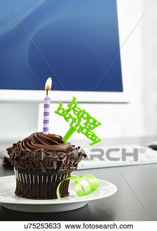 Stock Image - Birthday cupcake on desk. Fotosearch
