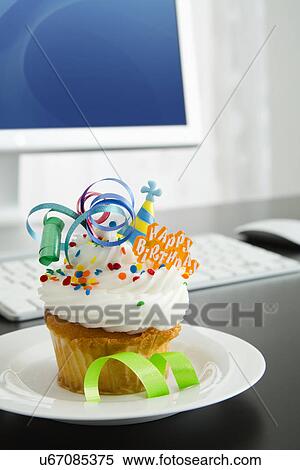 Stock Photography - Birthday cupcake on desk. Fotosearch