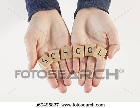 Stock Photo - Blocks with letters 'school' on boy's (10-11) hands, studio shot. Fotosearch