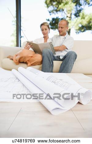 Stock Photo - Blueprints on table, couple in background. Fotosearch