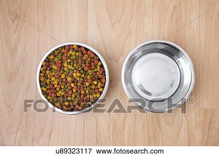 Stock Photo - Bowl of dog food and water on wooden floor. Fotosearch