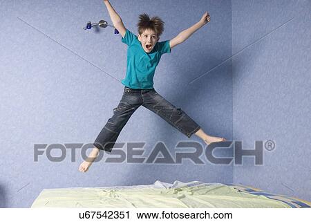 Boy (12-13) jumping on bed View Large Photo Image Stock Image - Boy (12-13) jumping on bed. Fotosearch