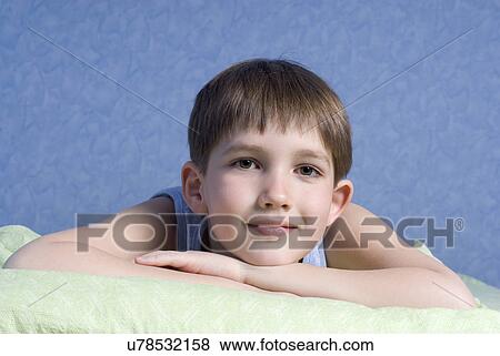 Stock Photo - Boy (12-13) lying on bed. Fotosearch
