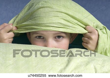 Stock Photography - Boy (12-13) peeking from under quilt. Fotosearch
