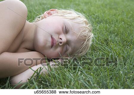 Boy (4-5) sleeping on grass View Large Photo Image Stock Photo - Boy (4-5) sleeping on grass. Fotosearch
