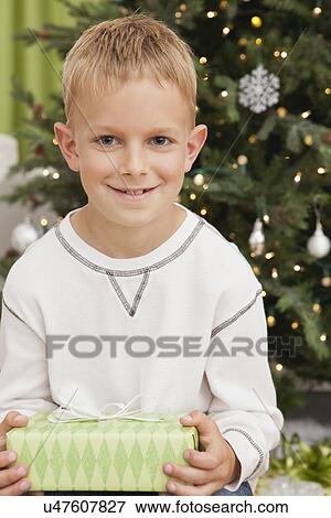 Boy (8-9) holding christmas present View Large Photo Image Stock Photo - Boy (8-9) holding christmas present. Fotosearch