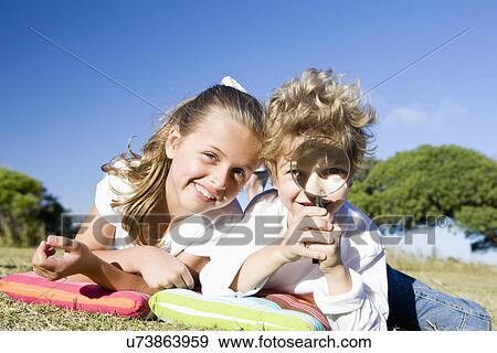 Boy and girl (8-9) lying down on blanket in park and playing, portrait View Large Photo Image Stock Photo - Boy and girl (8-9) lying down on blanket in park and playing, portrait. Fotosearch