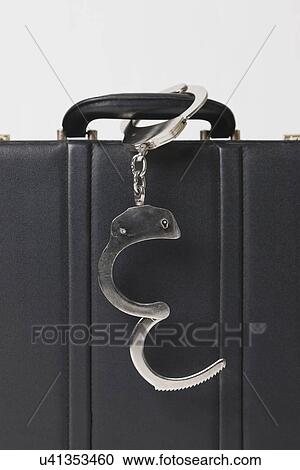 Stock Image - Briefcase with handcuffs locked to handle, close-up. Fotosearch